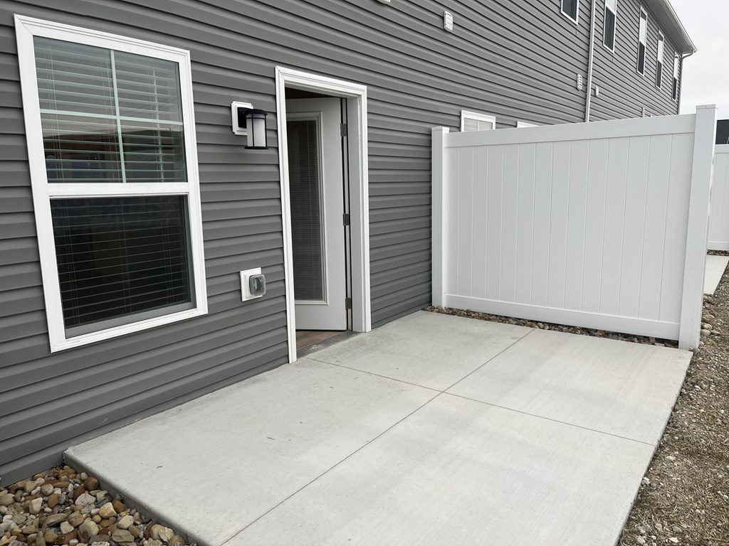 the front door of a grey house with a white garage door